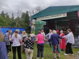 Na zdjęciu mieszkańcy wraz z pracownikami podczas wspólnego tańca przed sceną podczas Rycerskiego Pikniku Jubileuszowego. 