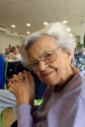 Na zdjęciu uśmiechnięta mieszkanka, p. Zosia ze złożonymi rękami podczas występu dziewcząt