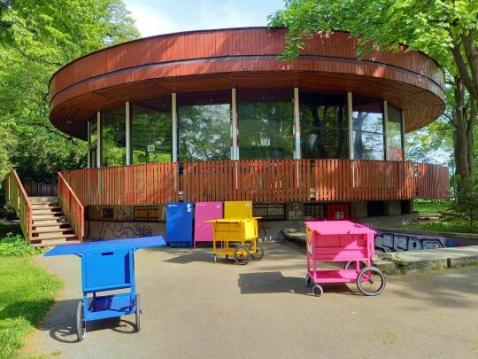 Wózki konsultacyjne w kolorach niebieski, miodowy, różowy na tle budynku Jordanówki.