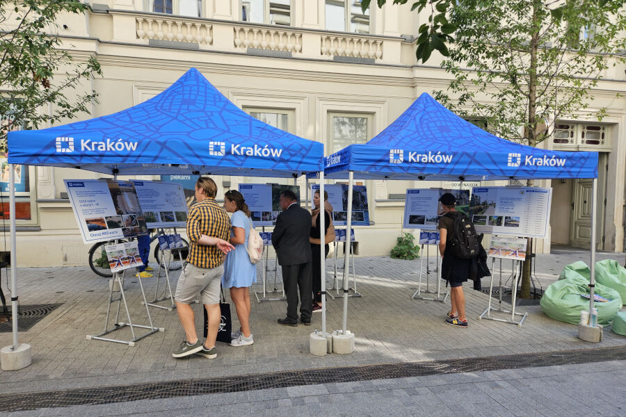 Zdjęcie wystawy o Budżecie Obywatelskim podczas pikniku „Wszystko o transporcie” przy ul. Krupniczej (ludzie oglądający plansze ze zdjęciami i opisami inwestycji z Budżetu Obywatelskiego).
