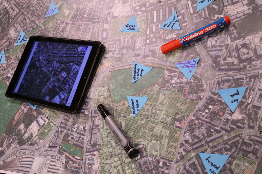 Widok fragmentu ortofotomapy Krakowa, na której leży tablet, pisaki i kolorowe karteczki