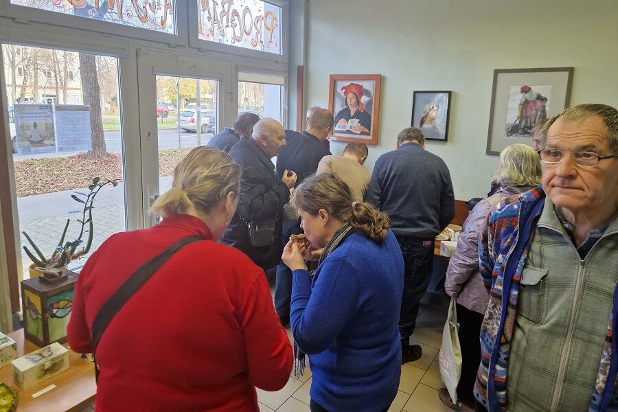Uczestnicy wystawy oglądają prace malarskie, ceramiczne i witrażowe.
