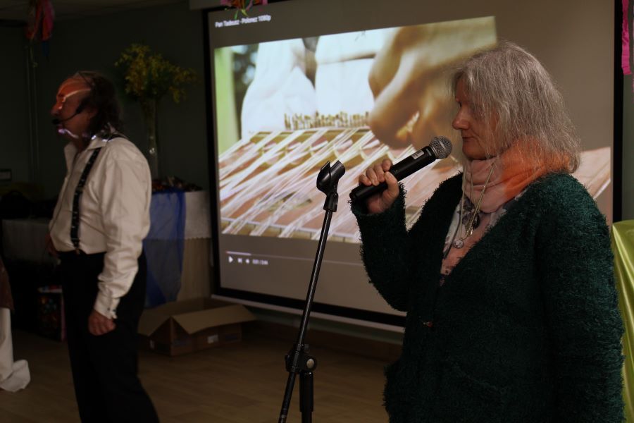 Kobieta i mężczyzna z mikrofonami na tle ekranu.