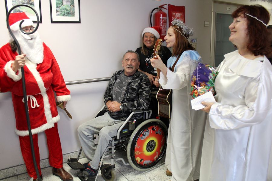 Kolędująca grupa kobiet i mężczyzn w przebraniach Mikołajów i aniołków.