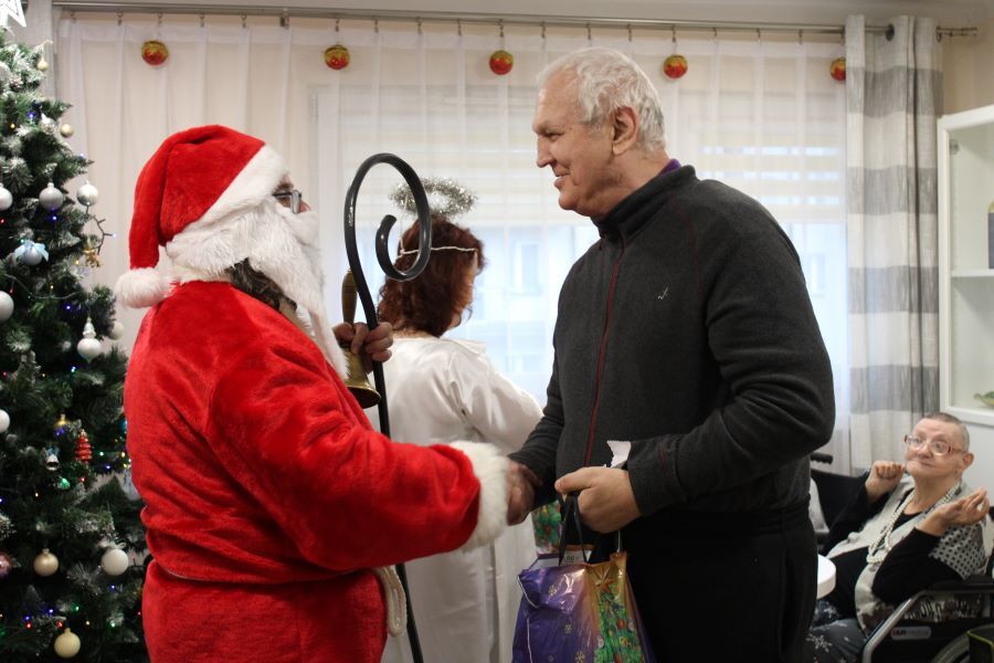 Mężczyzna witający się z osobą w stroju Mikołaja. 