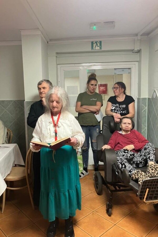 Stojąca kobieta z otwartą książką w dłoniach na tle grupy.