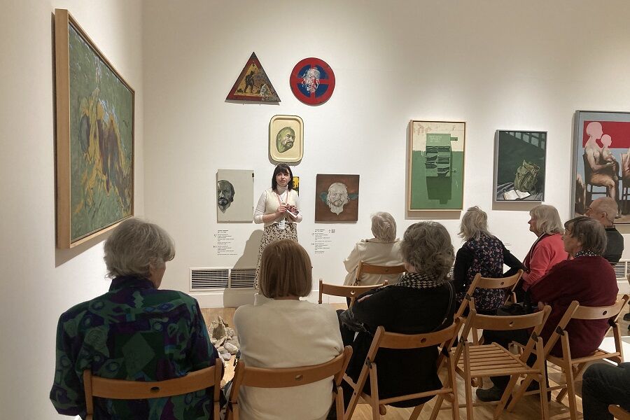 Seniorzy podziwiają kolekcję autoportretów Artysty Leszka Sobockiego wraz z Panią przewodnik, która tłumaczy zagadnienia związane z technikami tworzenia na różnorodnych materiałach.