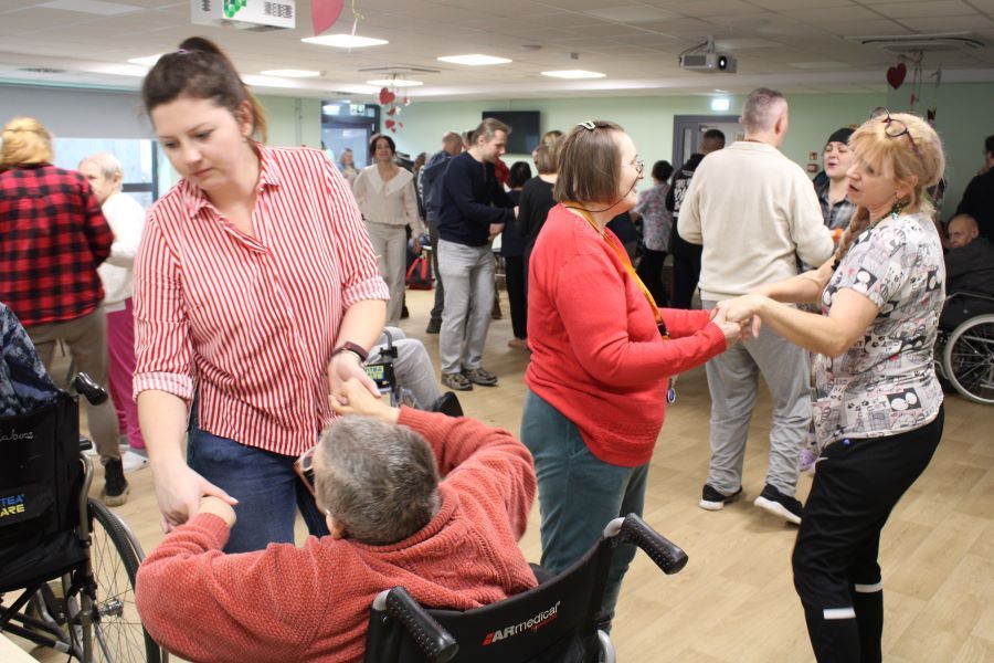 Kobieta w okularach stoi z mikrofonem w ręku. W tle widownia.