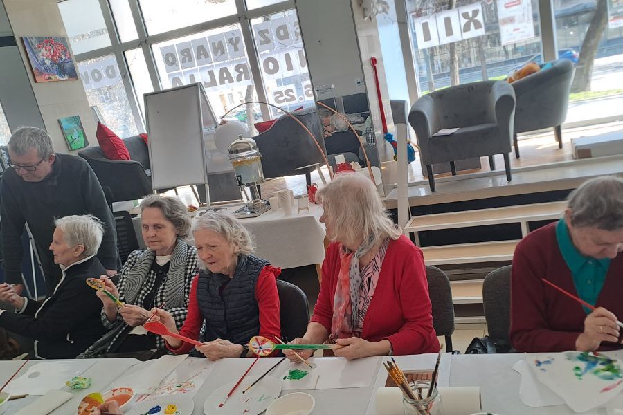 Seniorki malują łyżki farbami inspirując się wzorami ludowymi