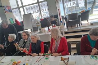 Seniorki malują łyżki farbami inspirując się wzorami ludowymi