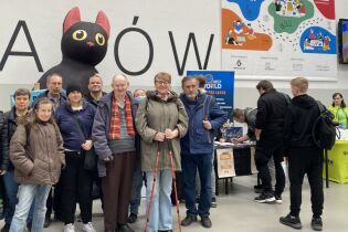 Uczestnicy na tle banneru reklamowego Targi Gier BookGame Kraków 2025