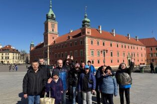 Grupa kobiet i mężczyzn pozujących na tle zabytków.