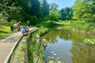 Uczestnicy odpoczywają nad stawem w Ogrodzie Botanicznym