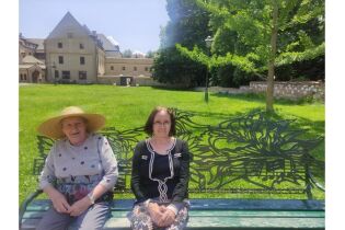 dwie kobiety siedzą na ławce. w tle kościół 