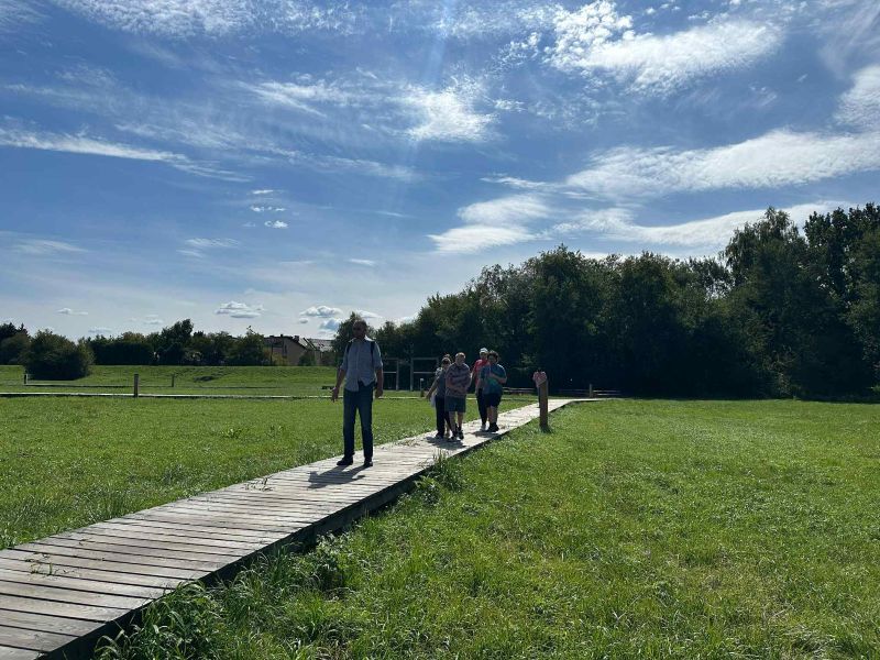 Uczestnicy spacerują po szlaku ścieżki sensorycznej