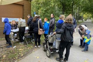 kilkanaście osób stoi w kolejce do stolika organizatora gry. 