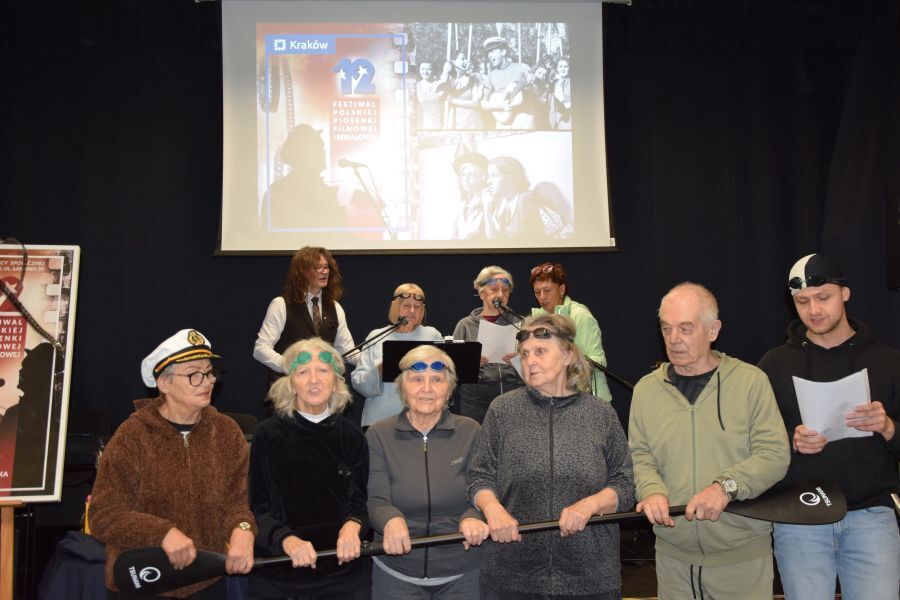 Seniorzy z Śds Vita występują na scenie w DPS Łanowa 39 i wykonują piosenkę „ Ach jak przyjemnie„