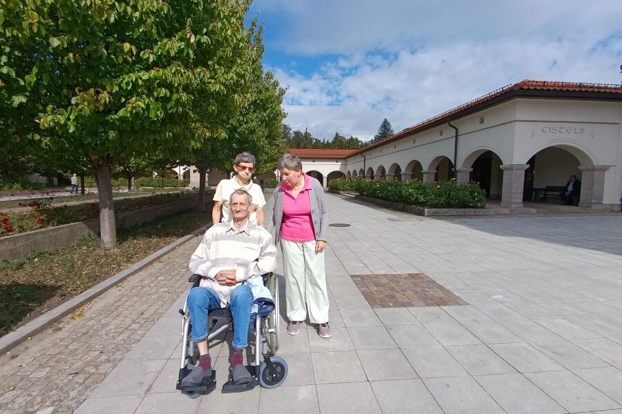 Na zdjęciu troje mieszkańców na terenie placu Bazyliki Krzyża Świętego przy alejce drzew. 