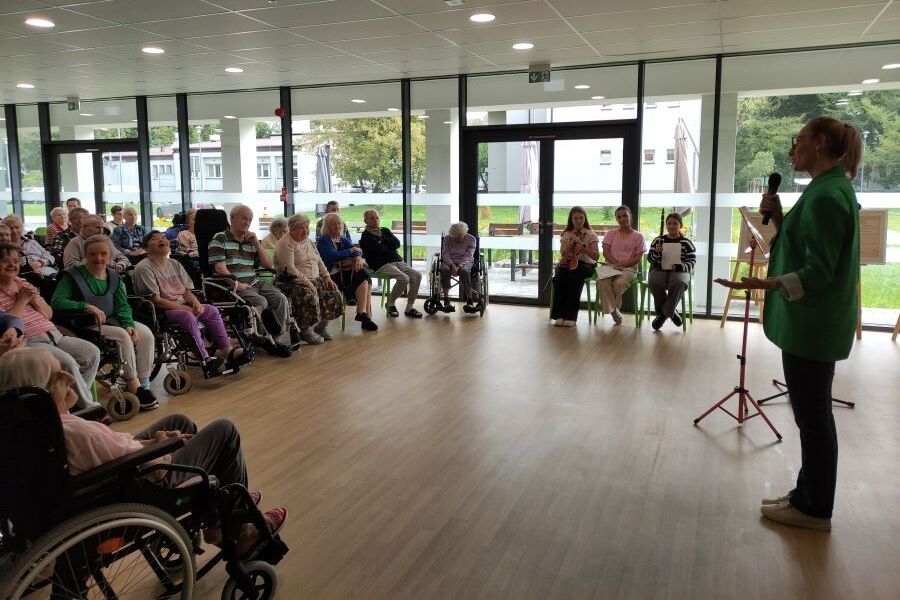 Na zdjęciu Pani Dyrektor wita zaproszone dziewczęta z Państwowej Szkoły Muzycznej I stopnia im. Michała Kleofasa Ogińskiego w Miechowie podczas urodzin mieszkańców. 