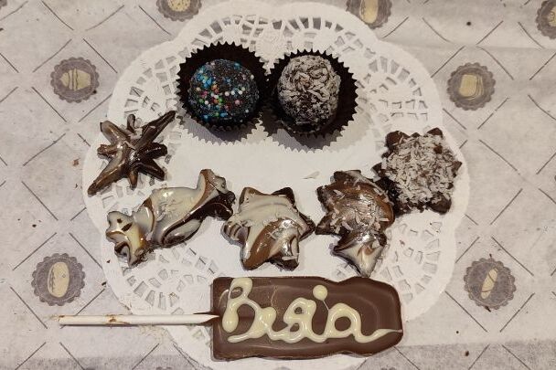 talerzyk czekoladek i pralin w posypce kokosowej, czekoladowy lizak Mikołaja z napisem wykonanym biała czekolada Basia.