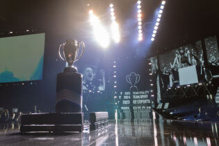 Ceremonia wręczenia zwycięskiej drużynie pucharu IEM Masters 2026. na pierwszym planie na postumencie stoi srebrny puchar. Na telebimach pokazana jest zwycięska drużyna Team Vitality. 